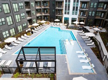 a swimming pool with lounge chairs and umbrellas at an apartment building